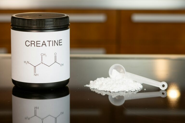 kreatin a bottle of creatine next to a spoon on a table